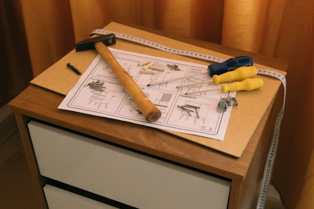 From above of wooden cabinet with drawers and paper instruction with tool to assemble it